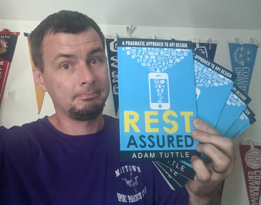 Adam Tuttle holding several paperback copies of his book, REST Assured