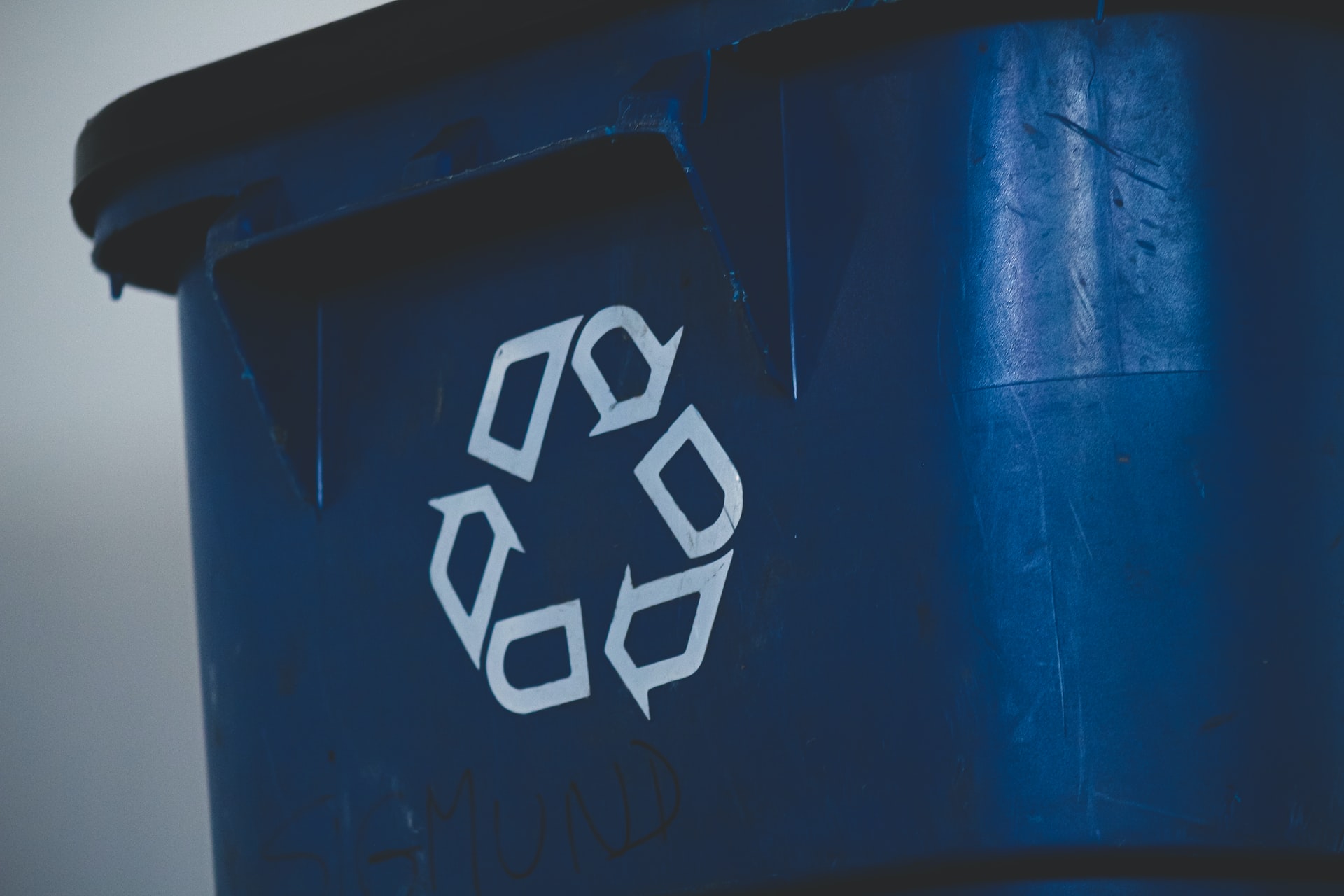 Close up photograph of the "recycle" symbol on a recycling bin